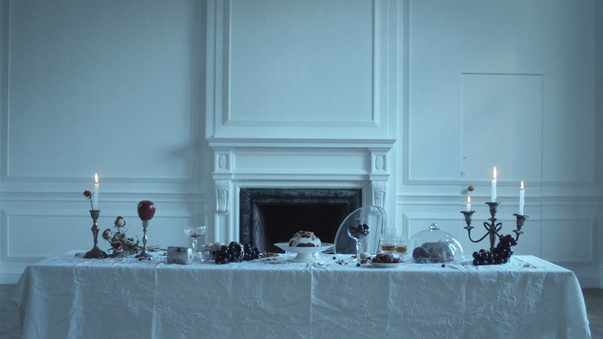 Candlelit banquet table with fruit and silver in a white paneled room