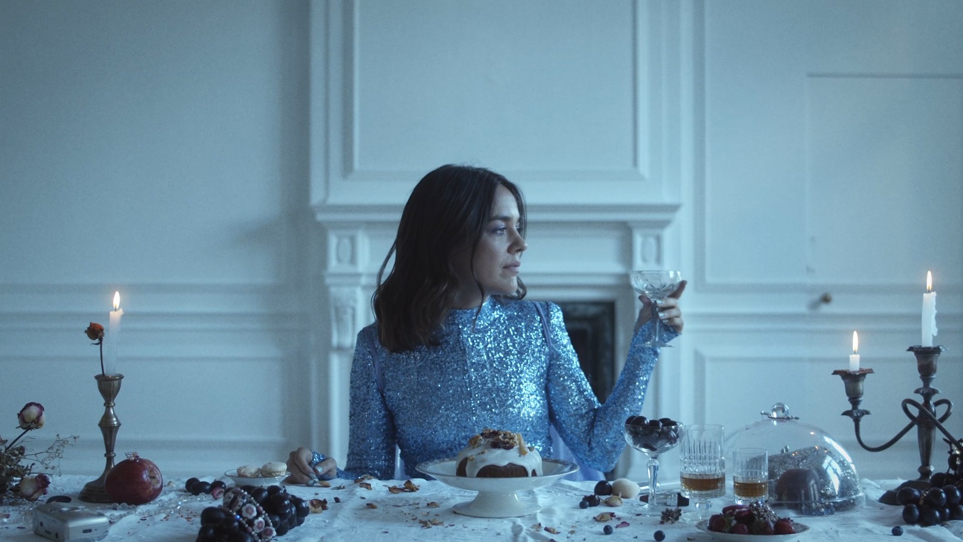 Singer in a blue sequined dress at the banquet table, holding a coupe