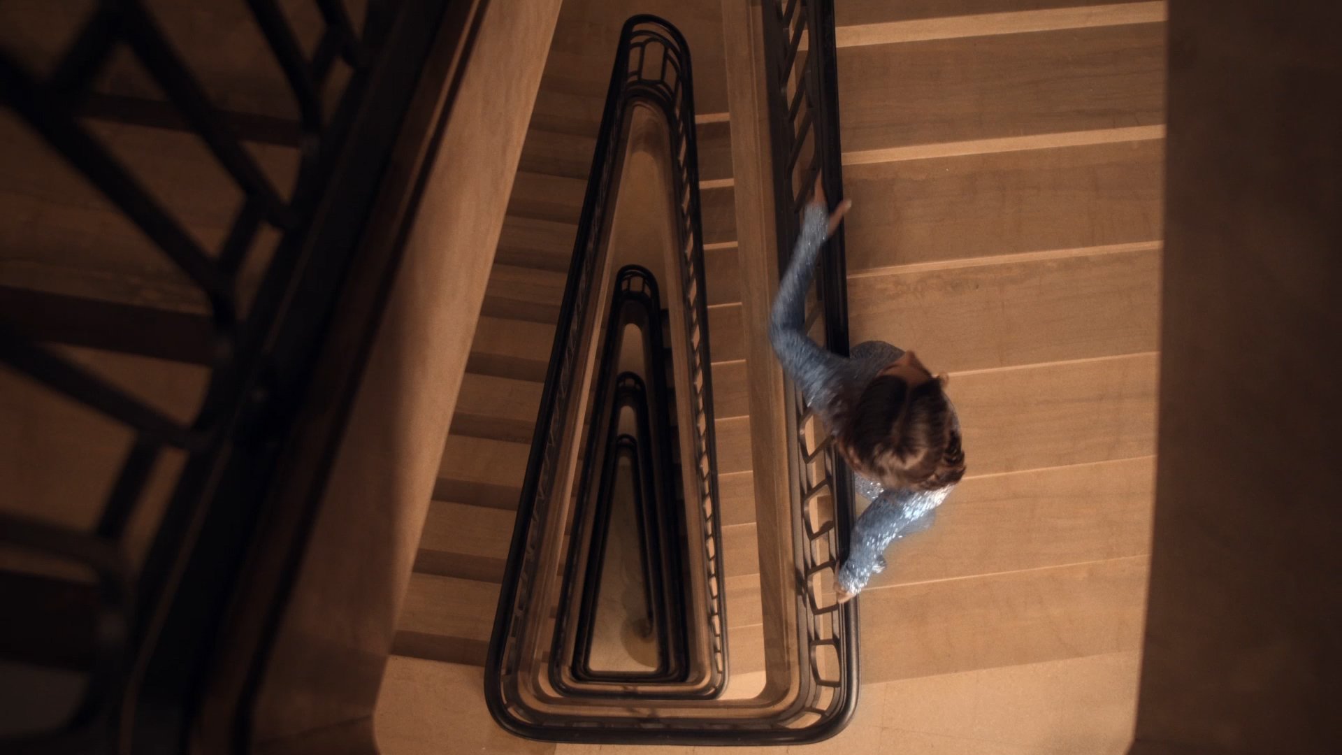 Overhead shot of a triangular stairwell, figure in blue sequins