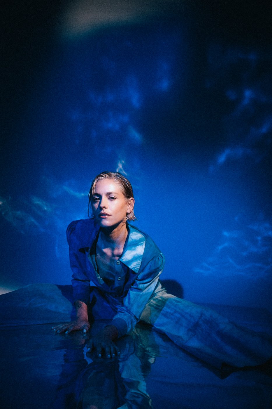 Portrait in a cloud-print shirt on reflective floor in blue light