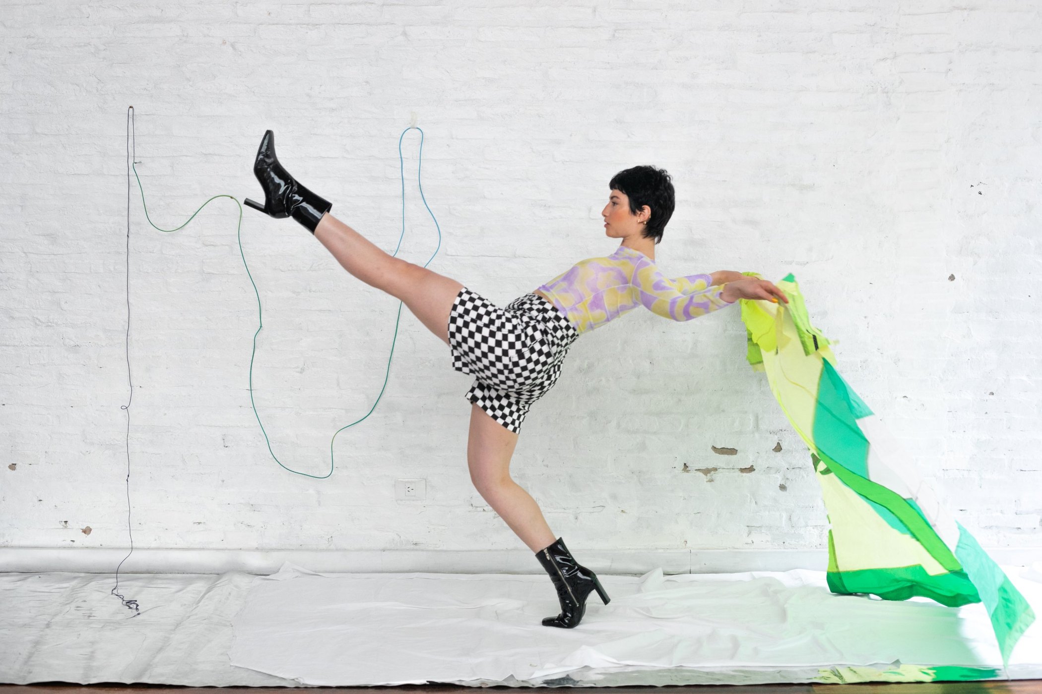 Model in high kick with green fabric trailing