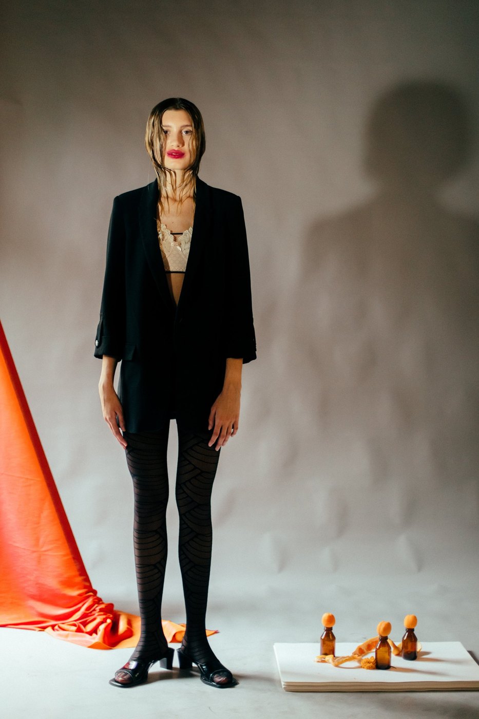 Model in a black blazer and patterned tights beside orange fabric